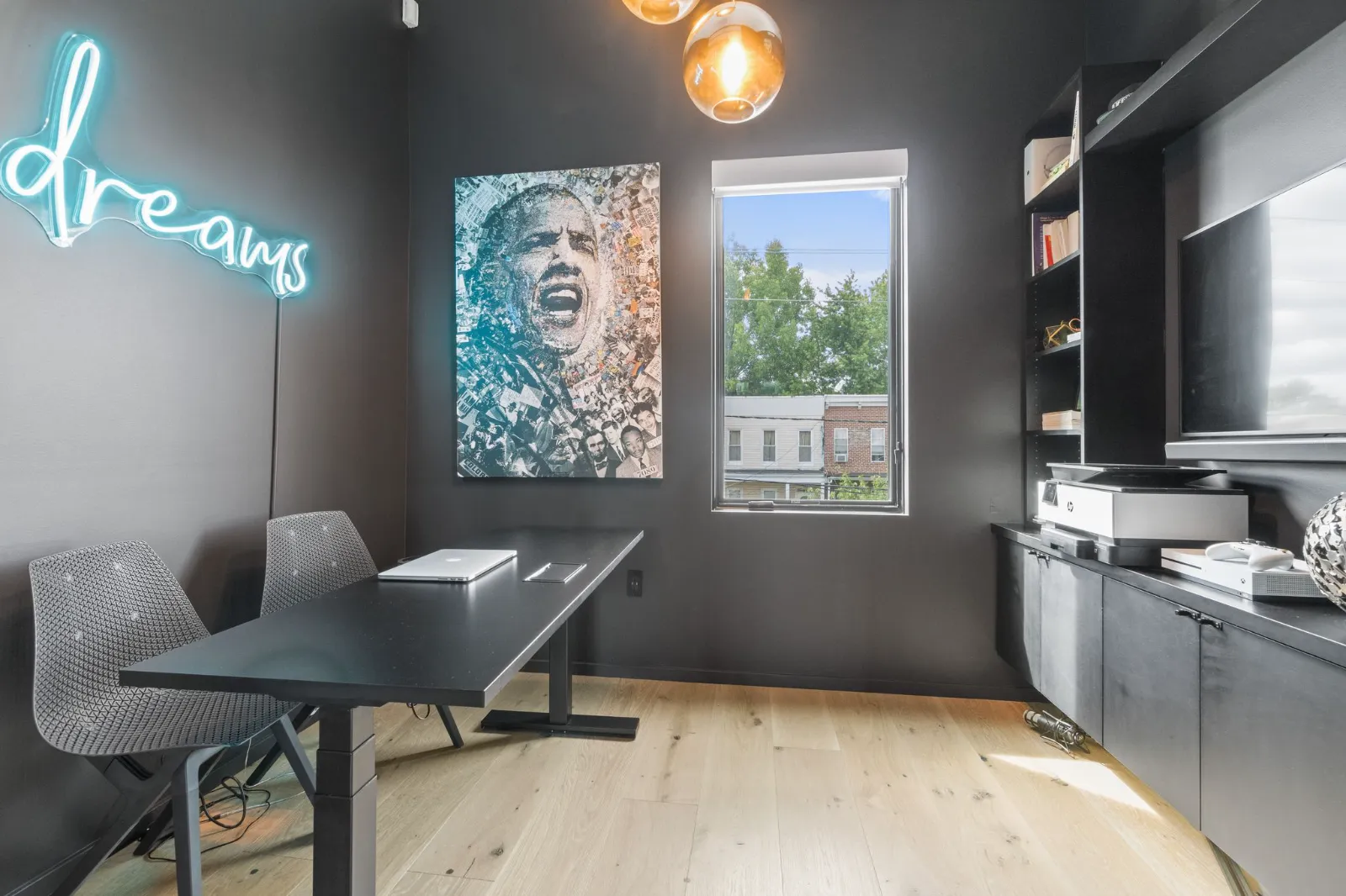 The office and media room with dark walls, a desk facing the window and built-in shelving