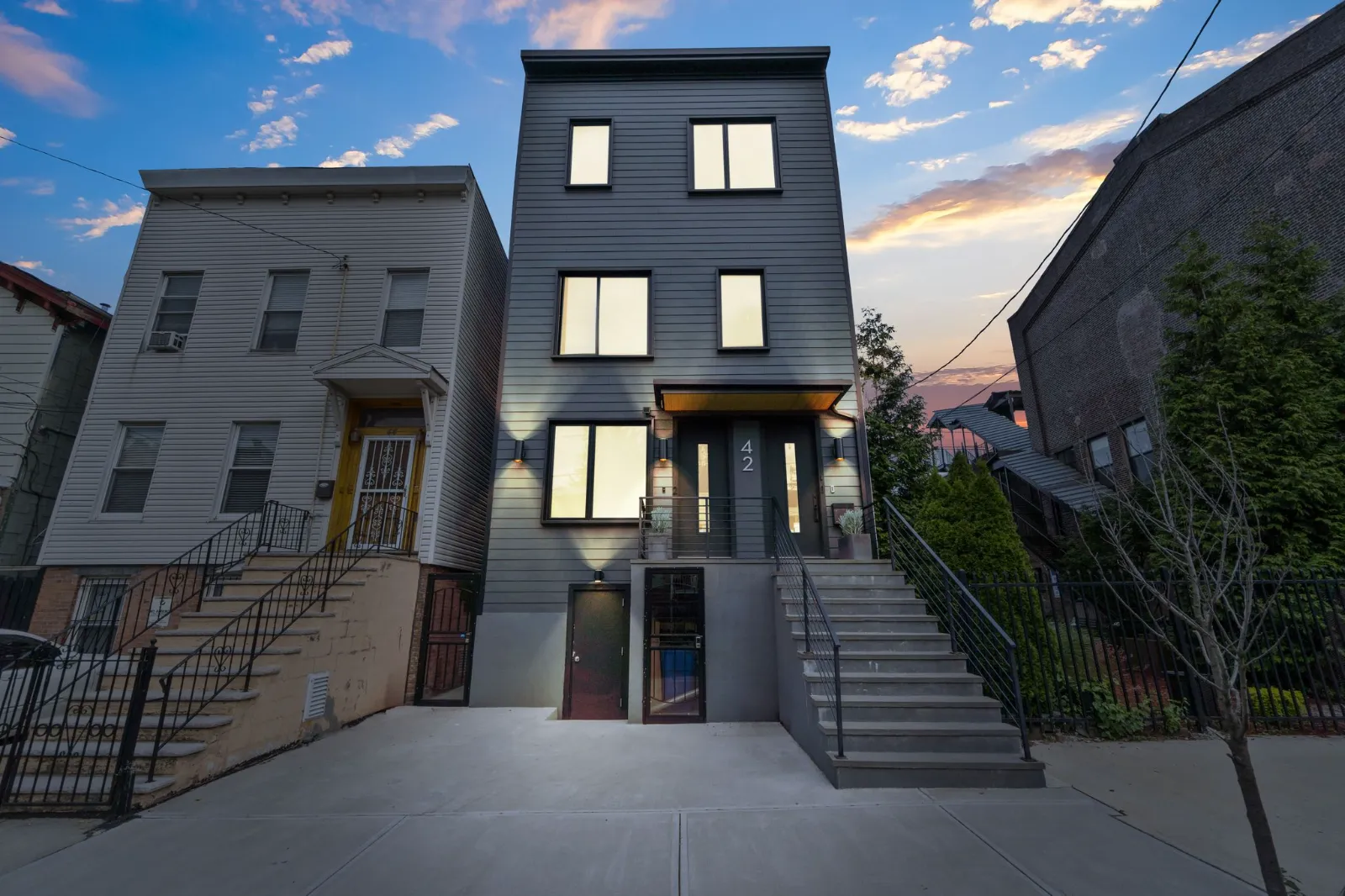 The facade of 42 Monitor Street at dusk, its windows lit, with a wide stoop and covered entry