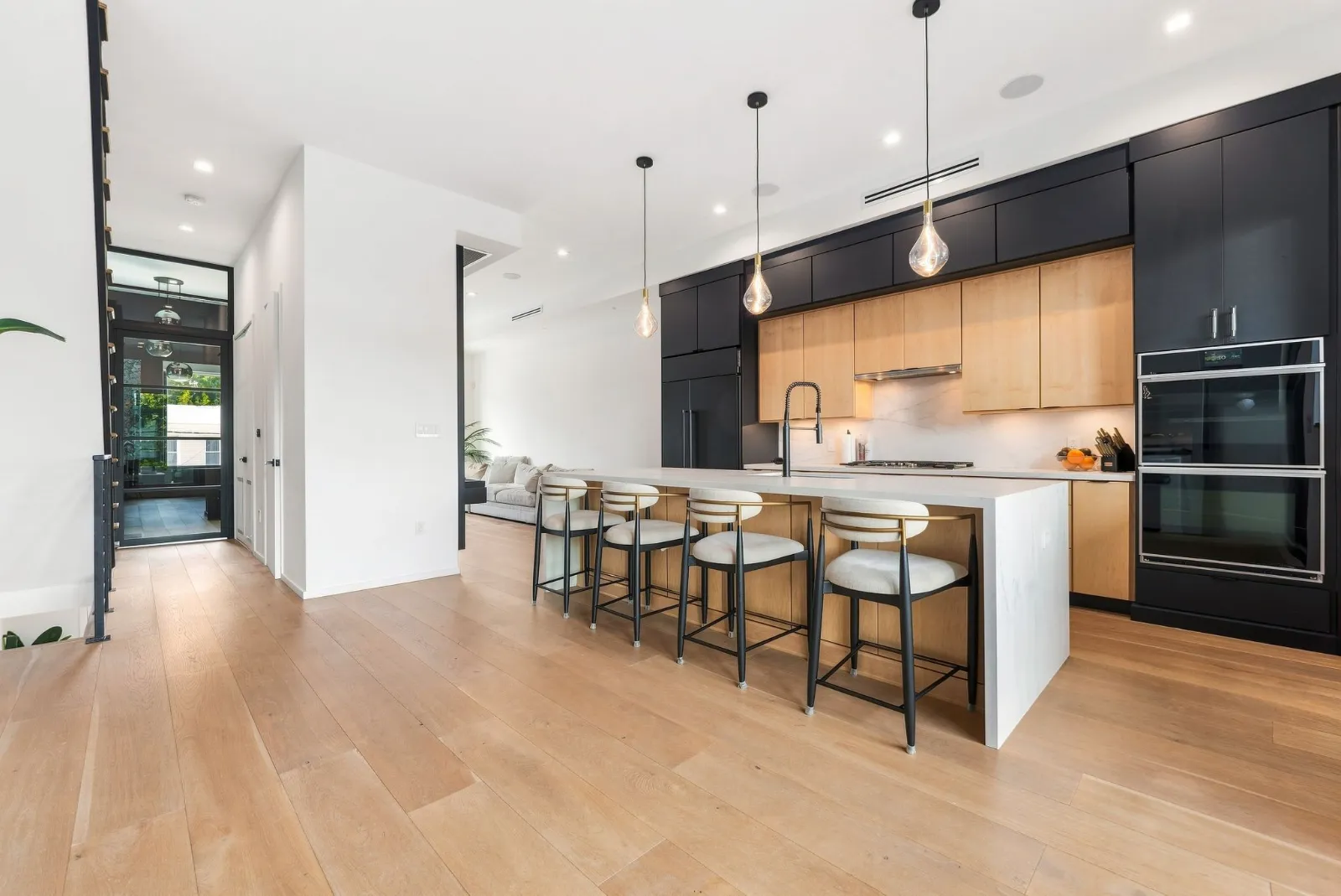 The ten-foot waterfall island with four counter stools, pendant lights and flat-panel cabinetry