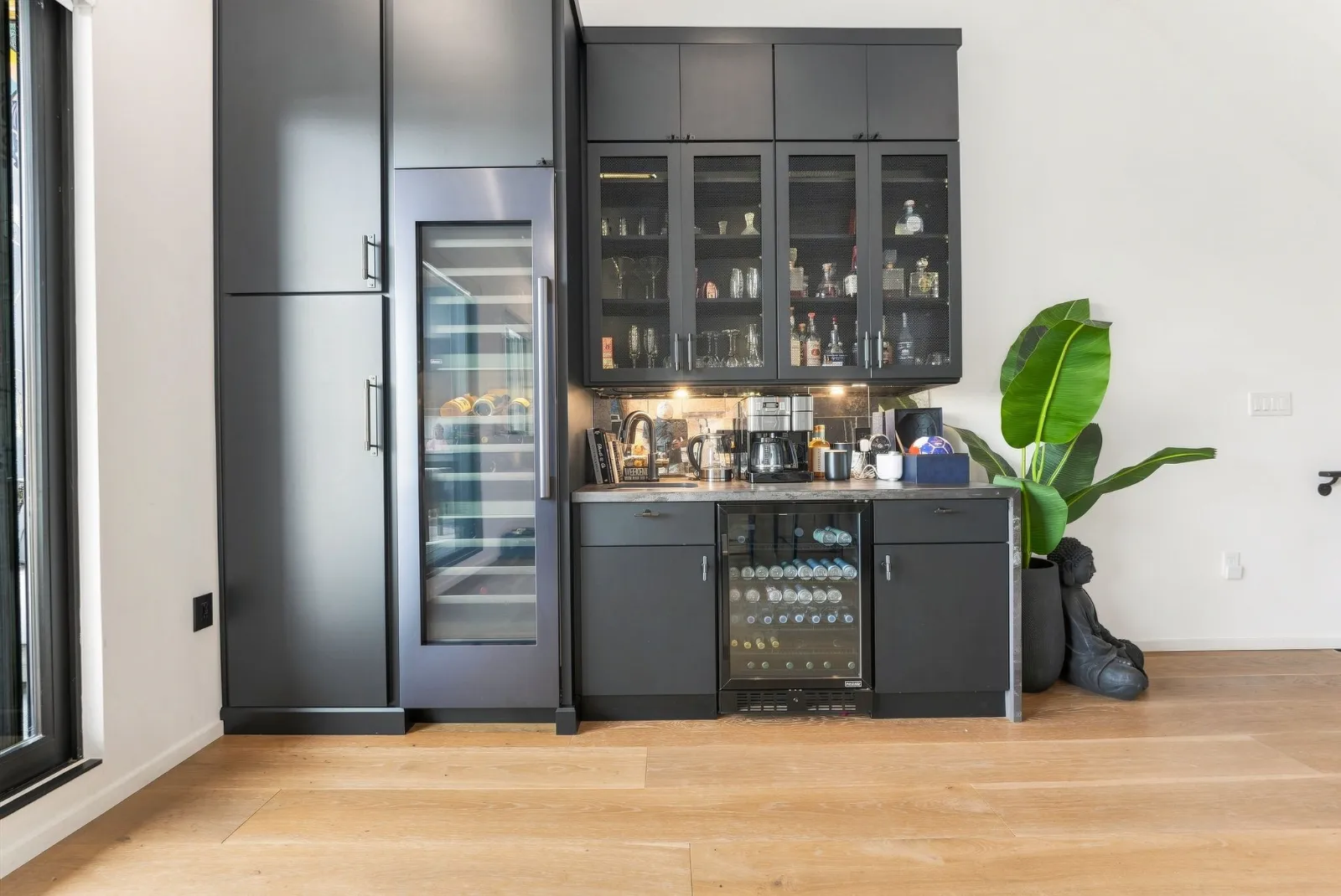 The wet bar with glass-front cabinets, wine refrigerator and tall pantry storage