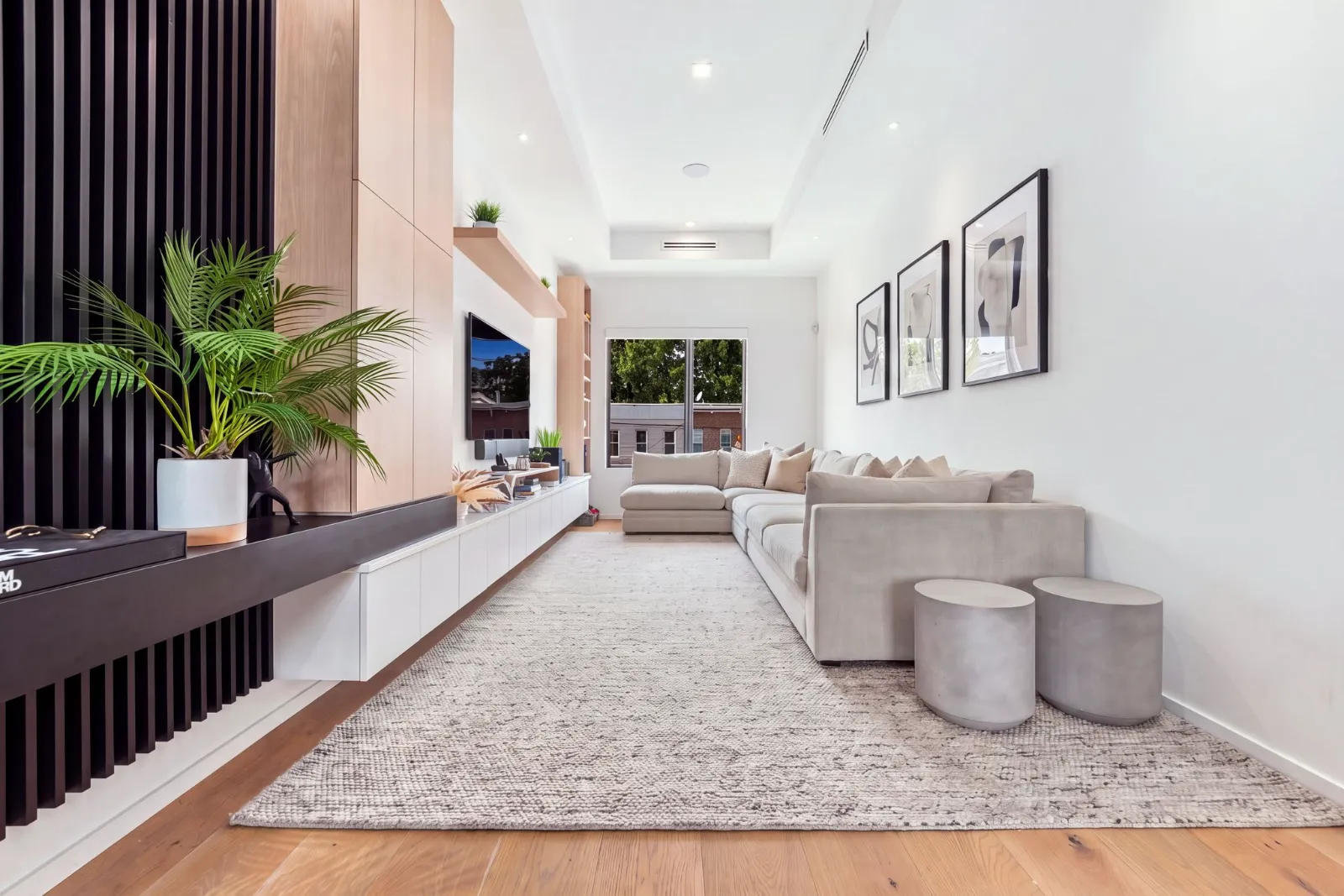 The living room with a long low media console, sectional sofa and white-oak floors