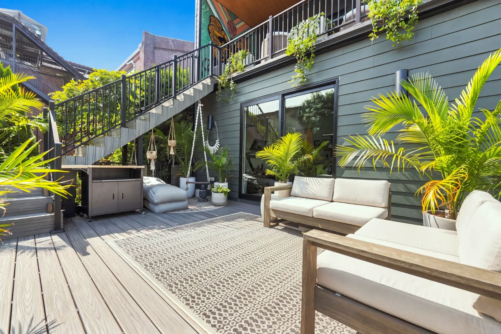 The garden deck with outdoor sofas, planters and a staircase rising to the upper level