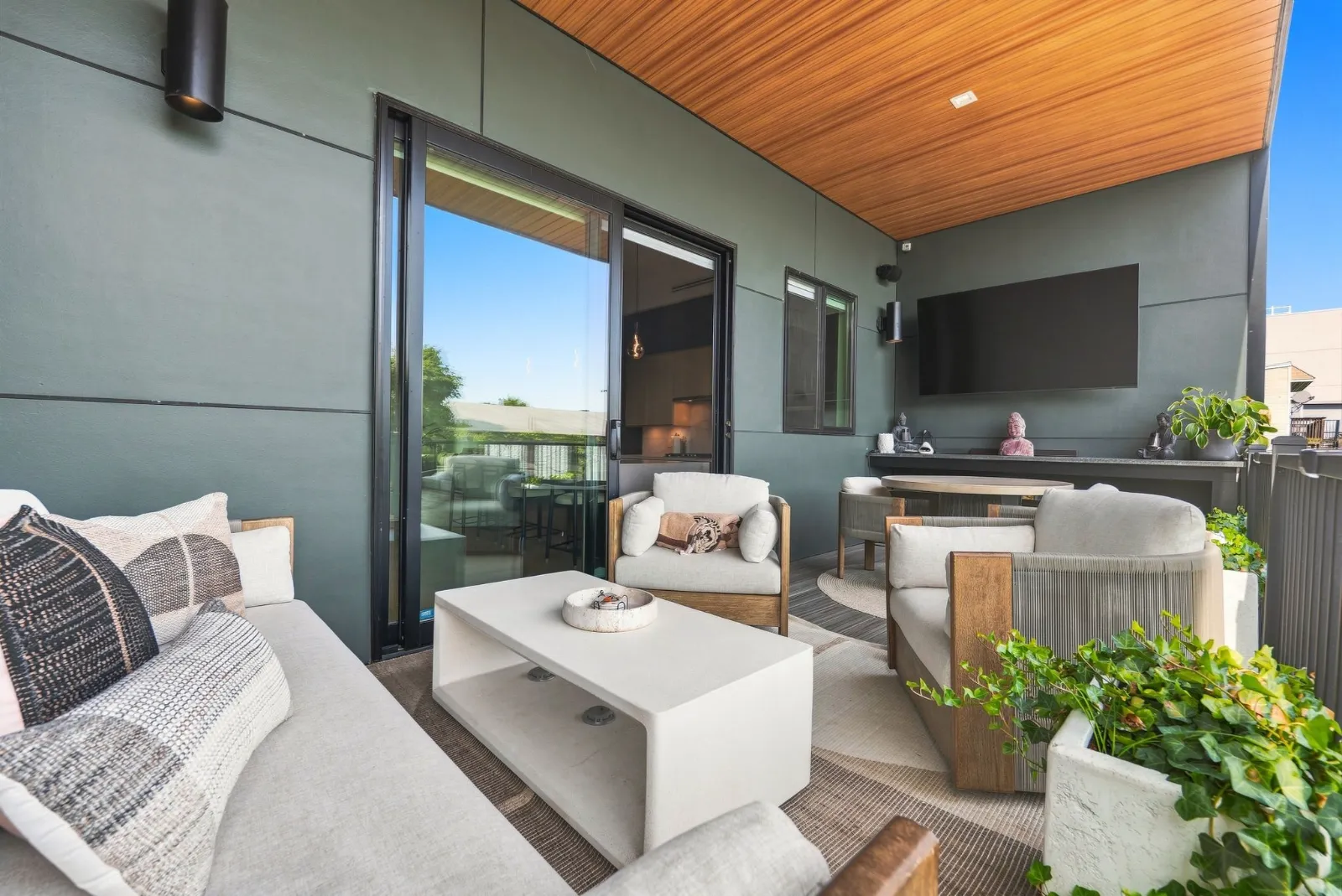 The covered veranda with a wood-clad ceiling, lounge seating and an outdoor television