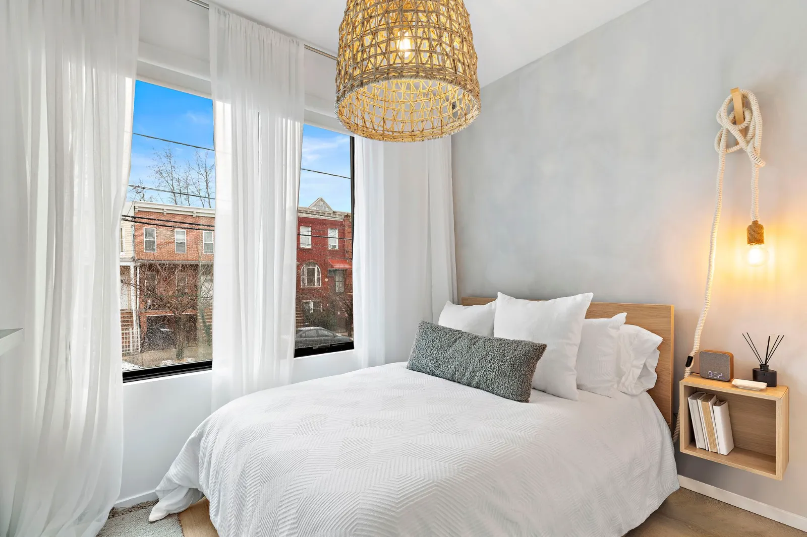 Second residence bedroom with tall windows, sheer curtains and a woven pendant