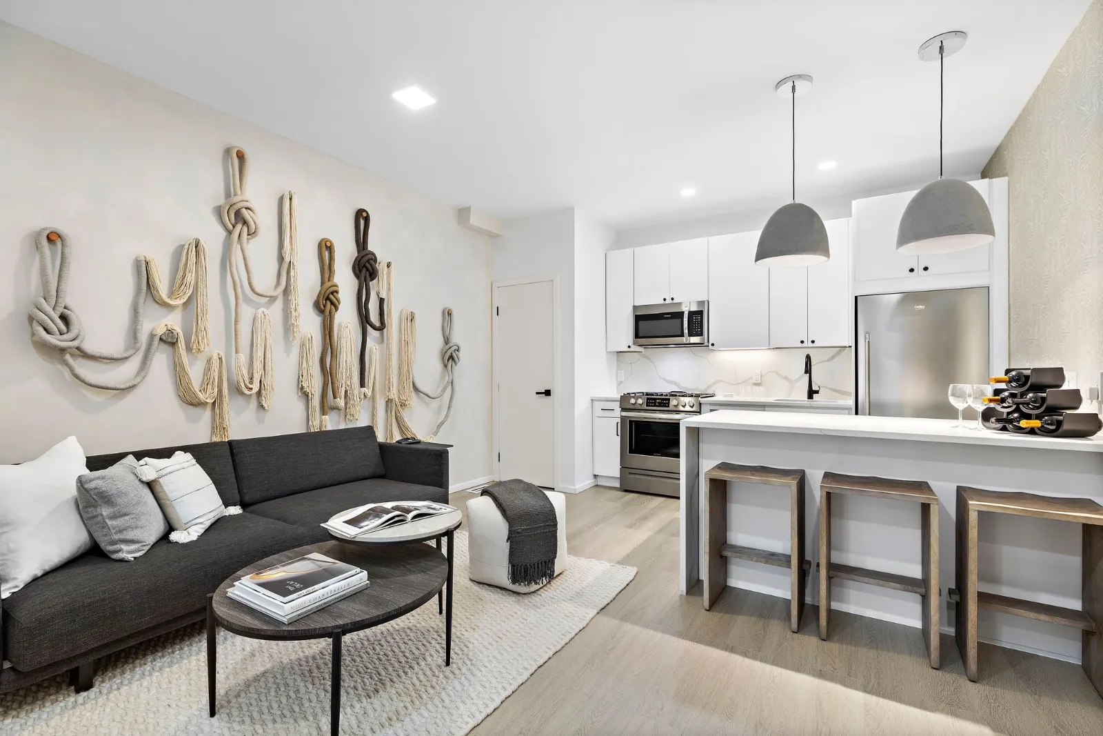 The second residence's open living room and kitchen with pendant lights and a stone island